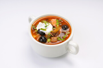 Traditional Russian soup solyanka in a white bowl on a white background