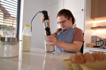Down syndrome woman baking in domestic kitchen