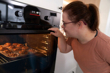 Down syndrome woman waiting for homemade cupcakes in the oven