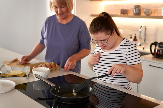 Down syndrome woman and her mother preparing breakfast together