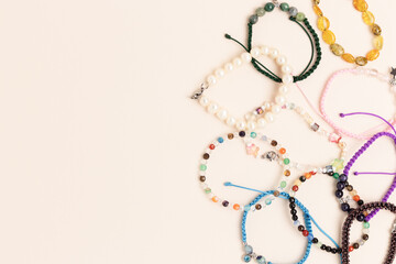 Multicolored handmade bracelets made of beads and cords on a beige background. Creative concept...