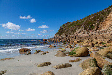 Rock formations on Porth Nanven beach on the Cornwall coast, with a blue sky overhead
