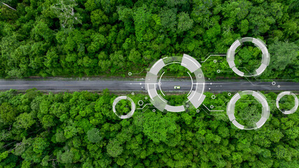 Aerial top view of green electric vehicle car driving over straight forest road, EV car electric...