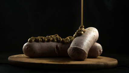 weisswurst close up. exquisite freshly cooked and boiled Bavarian weisswurst. covered in mustard. Typical Germanic sausage hot and steaming with mustard