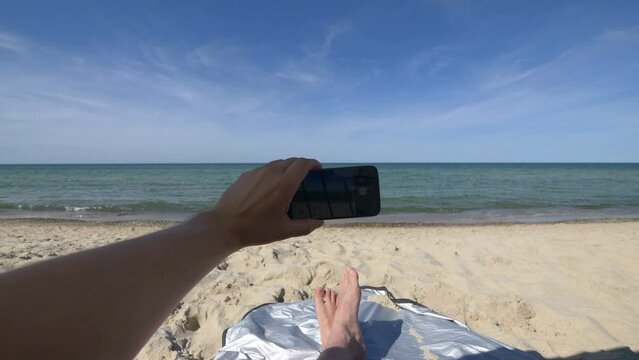 Tourist Capturing Photos and Recording Video from a Tent on a Beach by the Sea in 4k slow motion 60fps