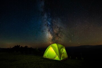 Night camping in mountains under starry sky and Milky way. Concept of traveling and hiking.