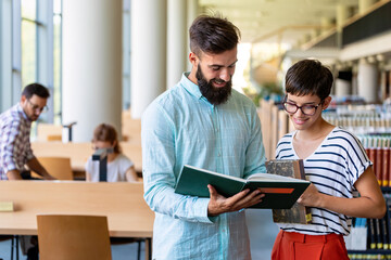 Happy university students studying with books in library. Group of multiracial people in college