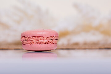 Delicate pink macaron cookie on a white table amidst white boho flowers. Perfect for bakery banners and elegant event invitations.