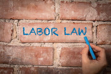 Labor Law. Text written with blue chalk on a red brick background