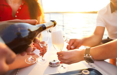 Happy friends with glasses of champagne on yacht