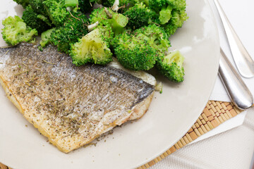 Dish of fried dorado fish fillet with boiled broccoli