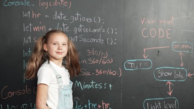 Caucasian girl writing blackboard and turnaround to looking at camera while standing at board with engineering prompt or coding, programing system written in STEM technology classroom. Erudition.