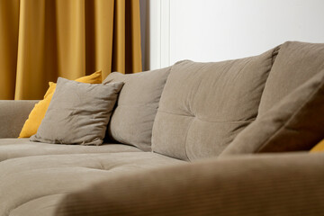 Grey comfortable sofa with mustard yellow cushion, curtains and coffee table, modern living concept.	