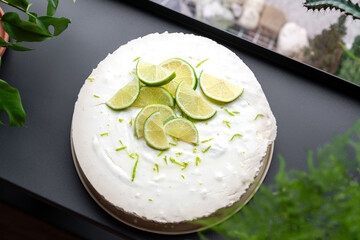 Limette Kuchen ohne backen aus dem Kühlschrank mit frischen Limetten als Garnitur am Fenster