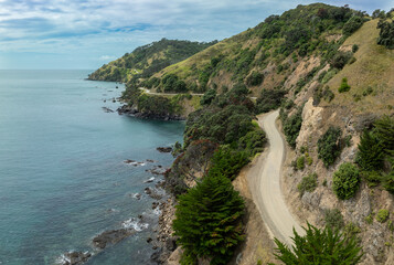 Coastline road and rocky foreshore and ocean. Port Waikato. Coromandel, Coromandel Peninsula, New Zealand.