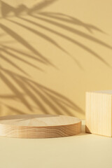 Fototapeta na wymiar Wooden scenes of different geometric shapes with a shadow of tropical palm leaves on a beige background. Premium podium for advertising your product. Showcase, display case.