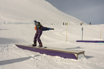 Snowboarder in the park on a box. Snow park box tricks. Winter jibbing in snwopark in France.