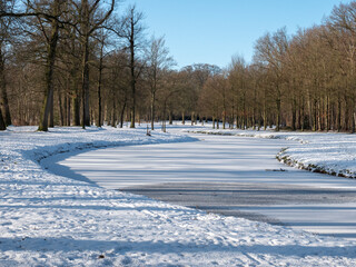 Fototapeta na wymiar Citypark with frozen river and snow landscape in Baarn, The Netherlands 