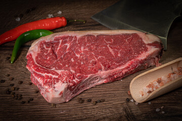 Raw beef steak with spices on a dark slate, stone or concrete background. Top view with copy space.