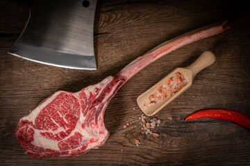 Raw beef steak with spices on a dark slate, stone or concrete background. Top view with copy space.