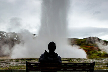 Strokkur geyser Iceland with man on bench