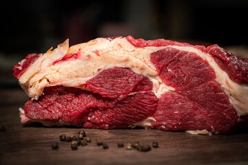 Fresh raw piece of beef meat, striploin steak on a black background, top view. Marbled piece of...