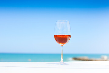 Glass of rose wine against blue water and sea