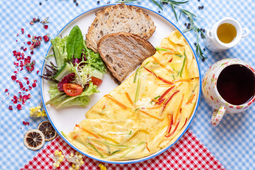Vegetable omelette with fresh salad on colorful fabric table