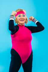 Happy and funny senior old woman wearing sportswear clothing on colorful background- Modern cool...