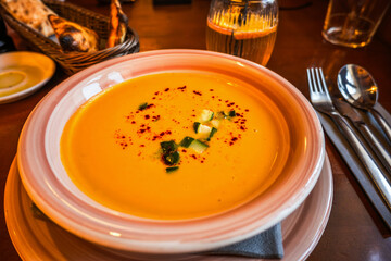 Creamy mixed carrot soup with zucchini on restaurant table.