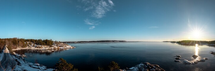 Fototapeta premium Panorama einer Bucht in Skandinavien bei winterlichem Sonnenuntergang am Meer