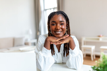 Portrait of a beautiful woman smiling at home. African woman in casual looking at camera with copy space. Cheerful mixed race girl relaxing at home with big laugh.