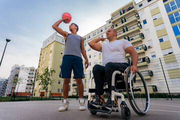 Mature man in the wheelchair coaching basketball to a young black man at the youth center before tryouts