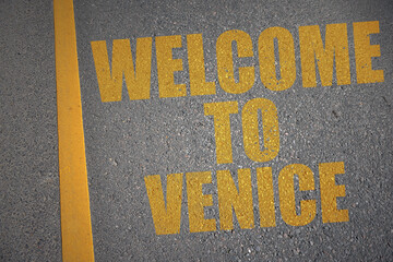 asphalt road with text welcome to Venice near yellow line.