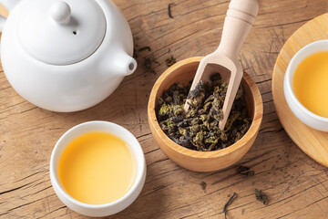 Tea leaves in bowl with tea set on wood table