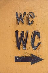 Closeup of wc text and arrow on old cracked wall paint texture background.