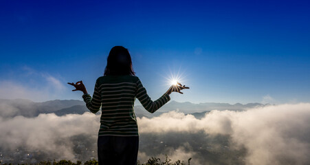 Panorama back view of woman is relaxingly practicing meditation yoga at top of misty mountain with rising sun in the summer to attain happiness from inner peace wisdom for healthy mind and soul