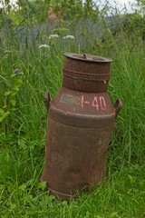 Obraz premium Old and rusty milk jug as a decoration outside in a garden.