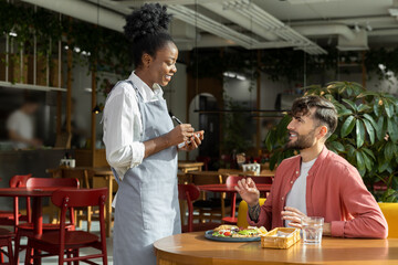 Fototapeta na wymiar African american waitress taking order from customer