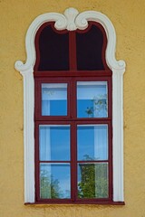 Closeup of red framed wood window on a stone building.