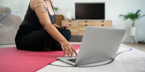 Women exercise on yoga mat and use laptops to watch workout clips. wellness home concept