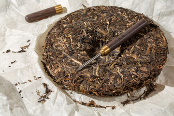 Round flat disc of puer tea with puerh tea awl. Pressed Chinese fermented Pu-erh tea.
