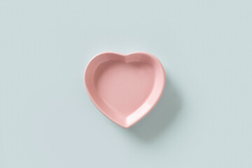 Valentines Day concept with empty pink plate heart shaped isolated on blue background. View from above. Greeting card.