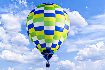 Colorful hot air balloon flying over blue sky with white clouds	