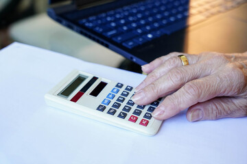an unrecognizable woman calculating the 2024 tax return with a calculator