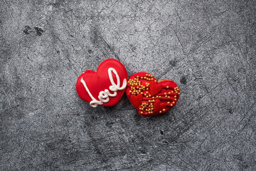 Homemade ginger cookies in the shape of a heart in red icing sugar. Delicious ginger cookies heart on a gray concrete background. Freshly baked gingerbread cookies for Valentine's Day.