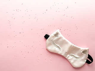 Women's sleep mask for eyes on pink background with confetti. Concept of insomnia treatment. Place for text 