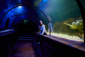 Young Girl Marvels at turtle Swimming Above in Oceanarium Tunnel