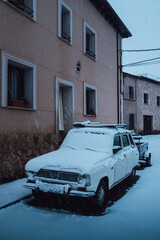 Old car parked on the street and covered in snow in winter