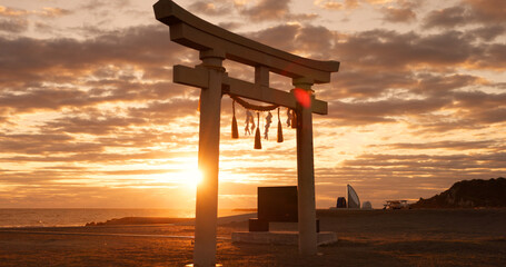 Torii gate, sunset sky and beach in Japan with clouds, zen and spiritual history on travel adventure. Shinto architecture, Asian culture and calm nature on Japanese landscape with sacred monument.